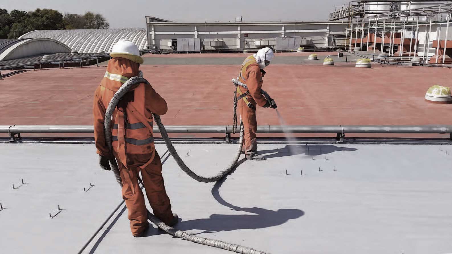 LINE-X applicators spray-coating a roof with protective polyurea coating